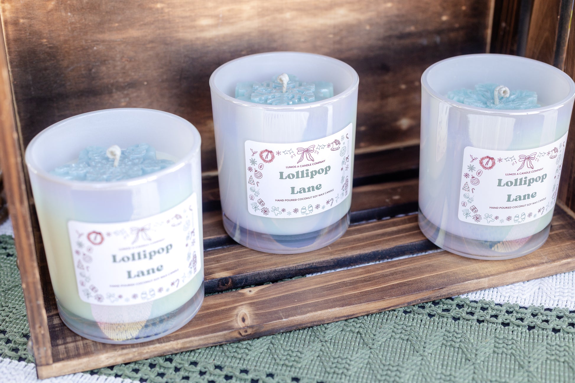 Three candles labeled 'Lollipop Lane' on a wooden tray.