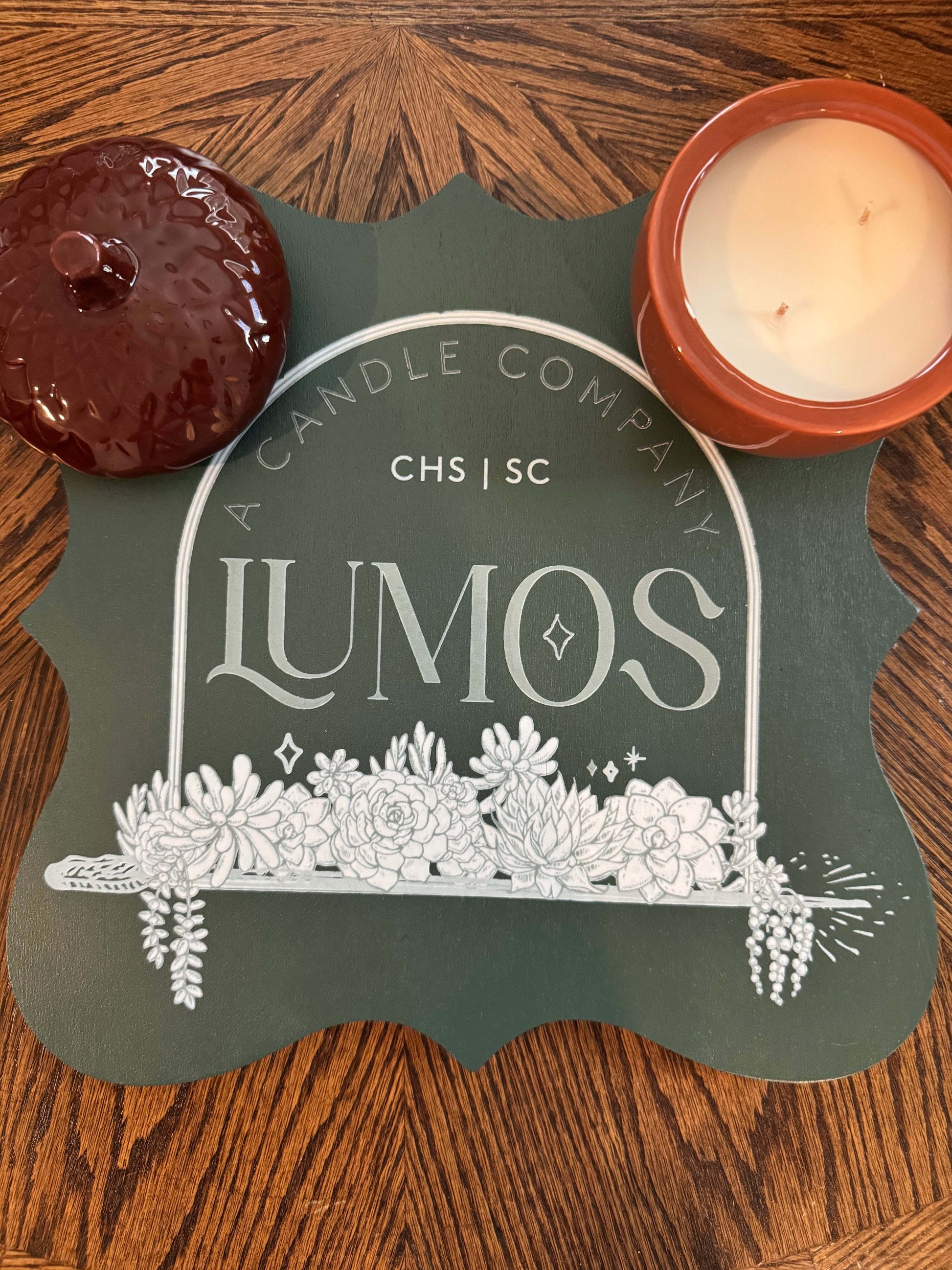 Fall scented candle in brown acorn ceramic vessel with lid on wooden table and Lumos sign