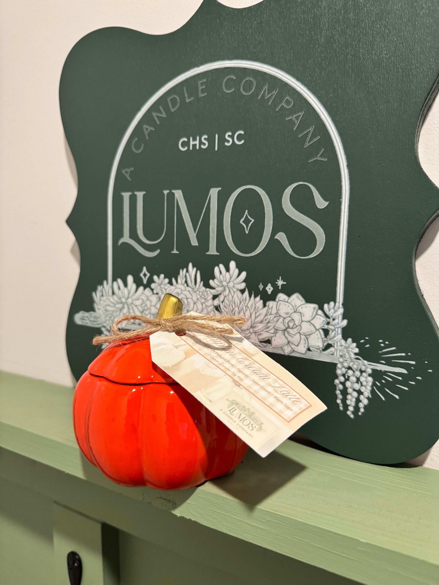 Limited edition fall scented candle in orange pumpkin ceramic vessel with rustic tag and cozy LUMOS branding in background