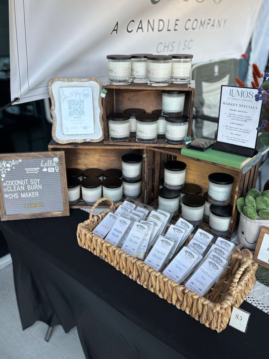LUMOS Hand-Poured coconut soy candles in glass jars with black lids displayed at market booth