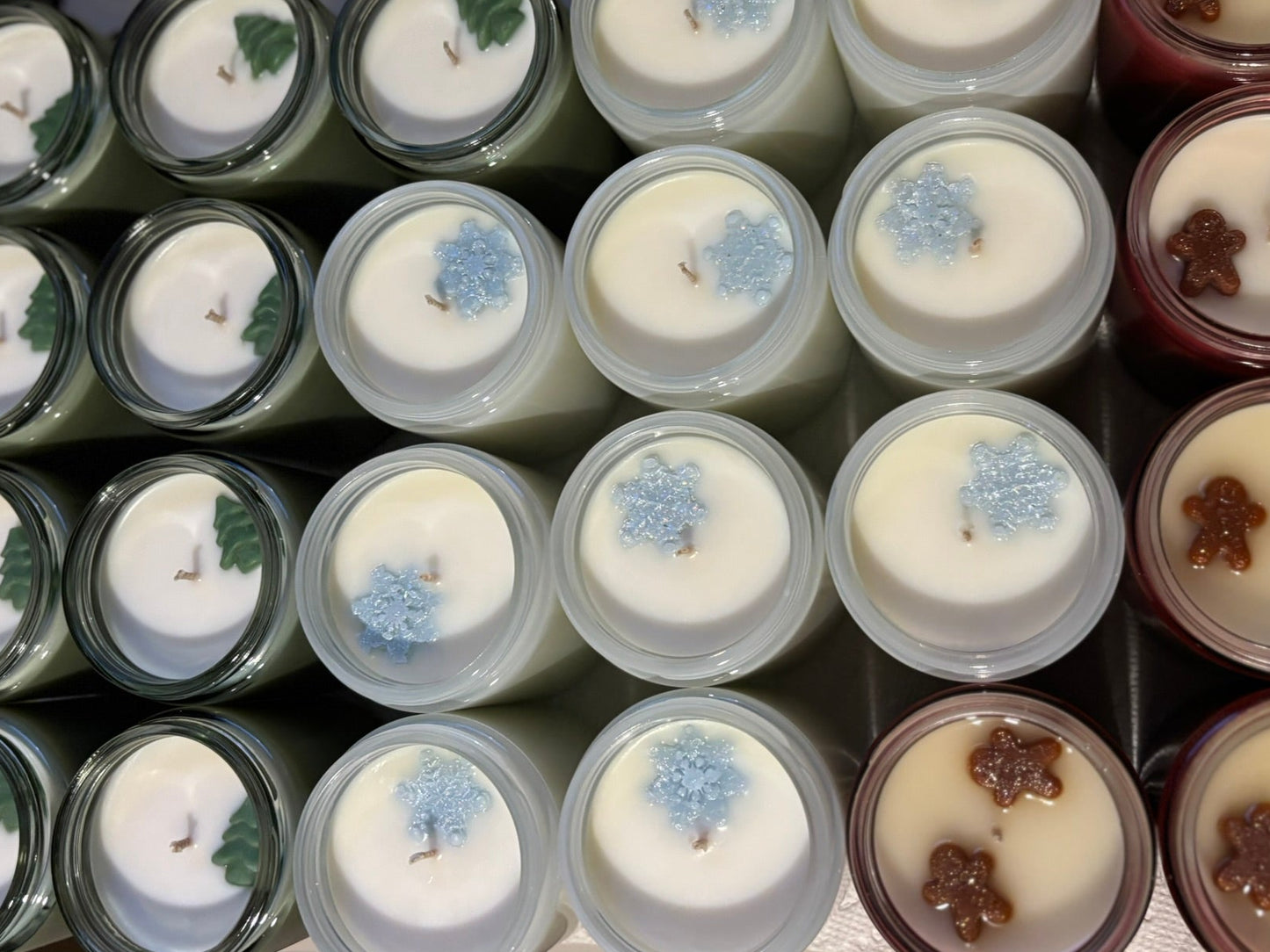 Assorted candles in various containers with decorative elements.