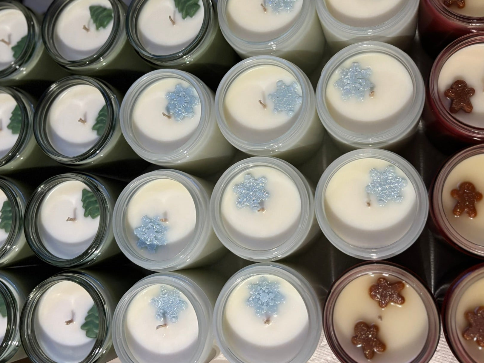 Assorted candles in various containers with decorative elements.