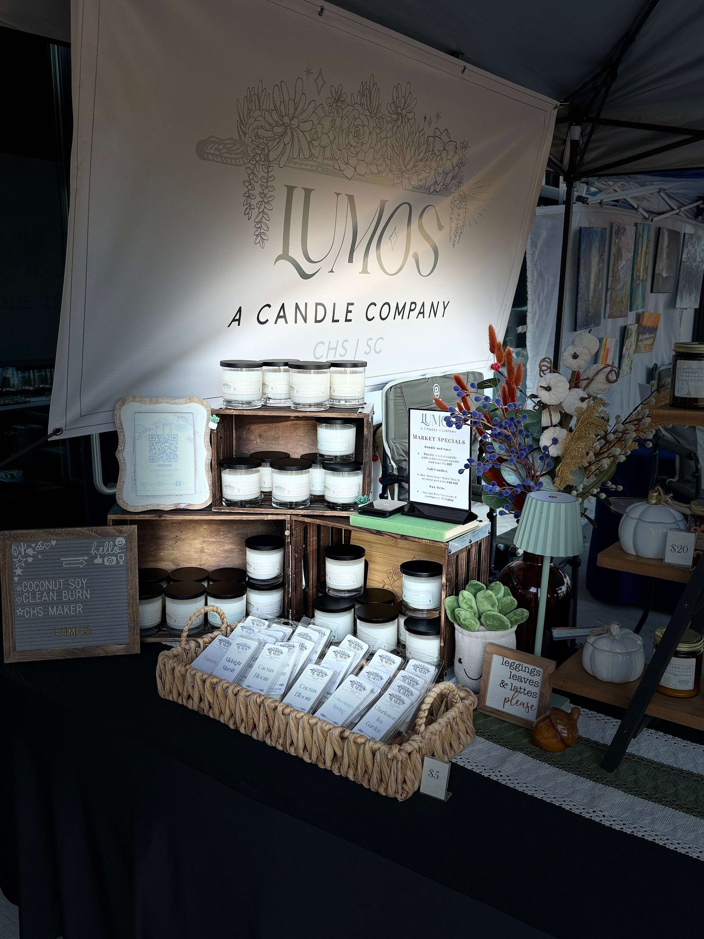 LUMOS Hand-Poured luxury coconut soy candles displayed at market booth with elegant packaging and decor