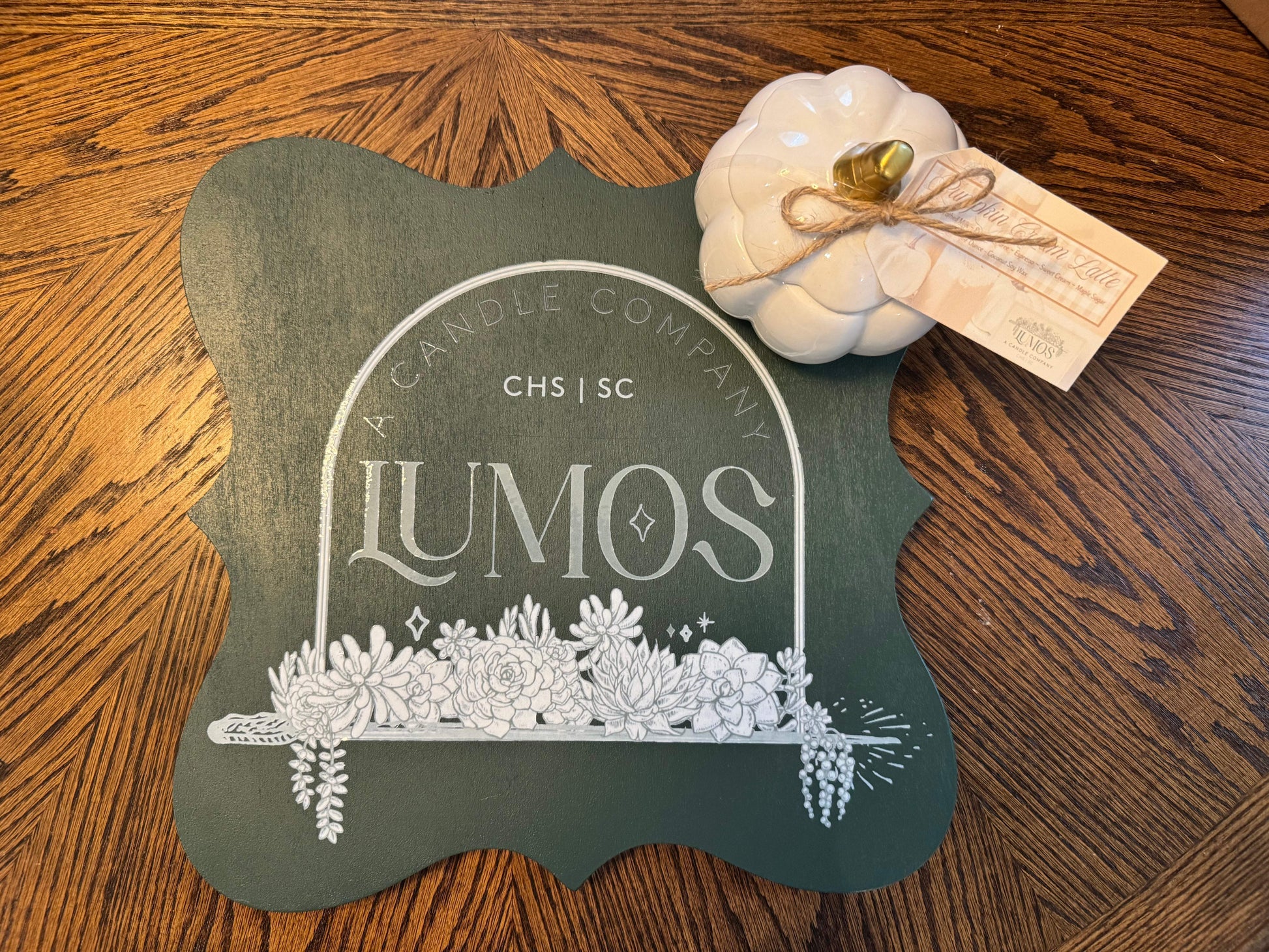 Fall scented candle in white pumpkin ceramic vessel on wooden surface with Lumos branding sign