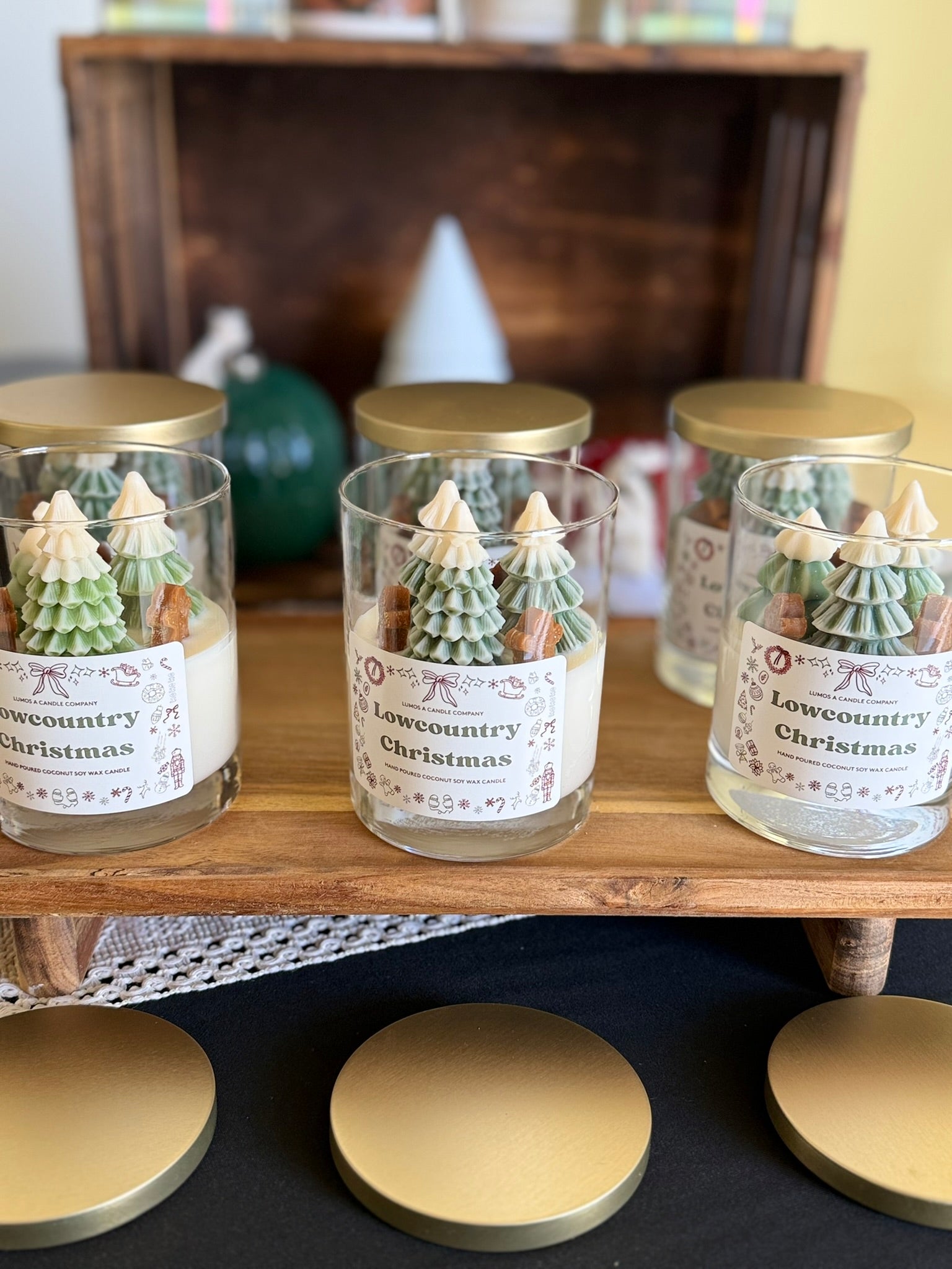 Decorative candles with Christmas tree designs on a wooden shelf.