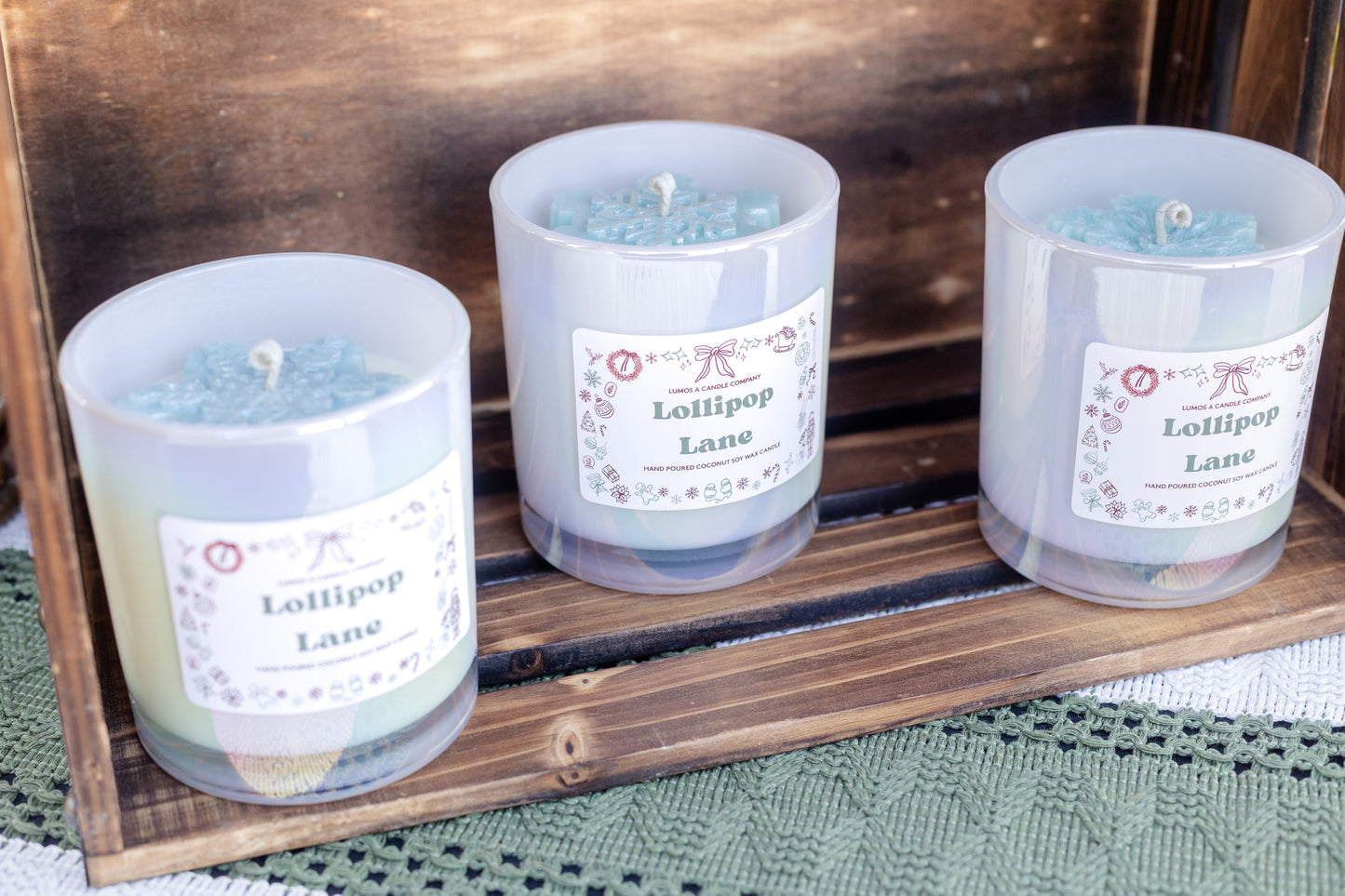 Three candles labeled 'Lollipop Lane' on a wooden tray.