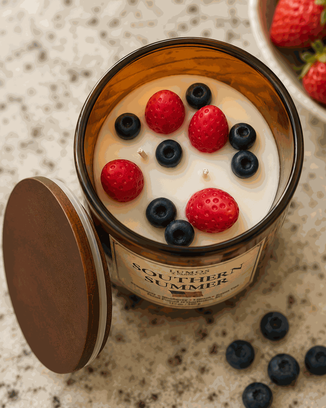 Candle with berries on top labeled 'Southern Summer' on a speckled surface.